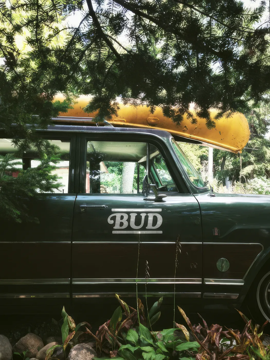 Carro antigo verde com a marca Bud na porta